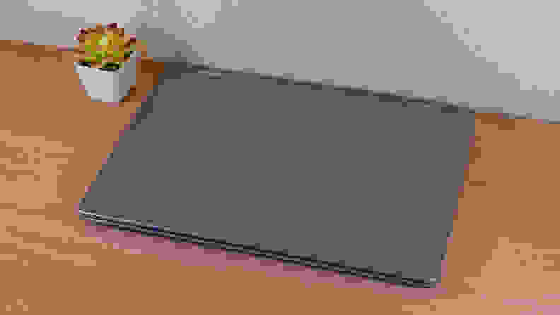 A closed silver laptop sits on a brown desk