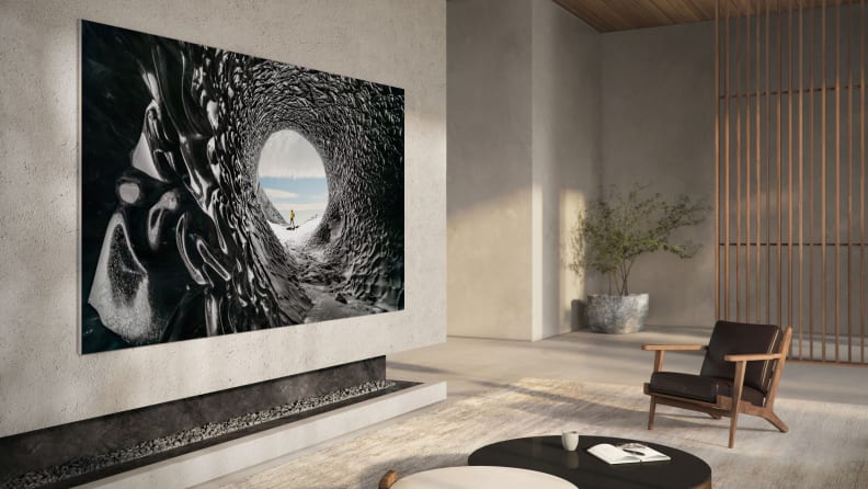 A modern living room with a huge Samsung TV hanging on the wall. The image on the screen looks almost like a painting.