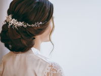Person displays bridal hair with accessory in bun.