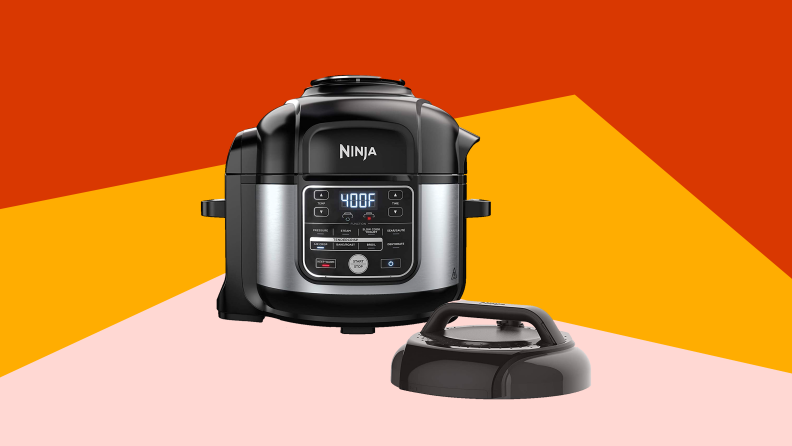 A Ninja brand pressure cooker with a lid in front of a pink, gold, and red background.