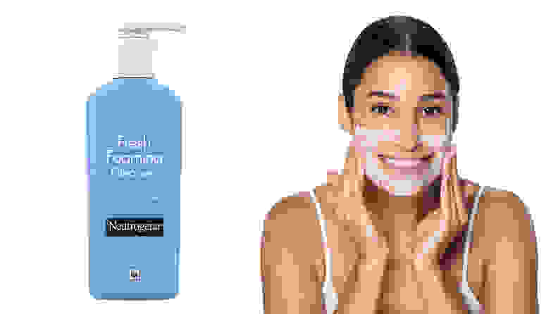 On the left: The blue Neutrogena Fresh Foaming Facial Cleanser stands on a white background. On the right: A person smiles directly at the camera as they lather the foamy white cleanser onto the bottom half of their face.
