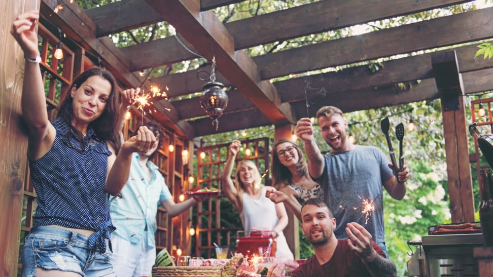 A group of friends spend a summer day barbecuing underneath a pergola