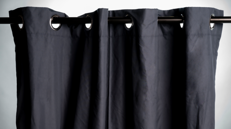 Black AmazonBasics blackout curtains hung against a white wall.