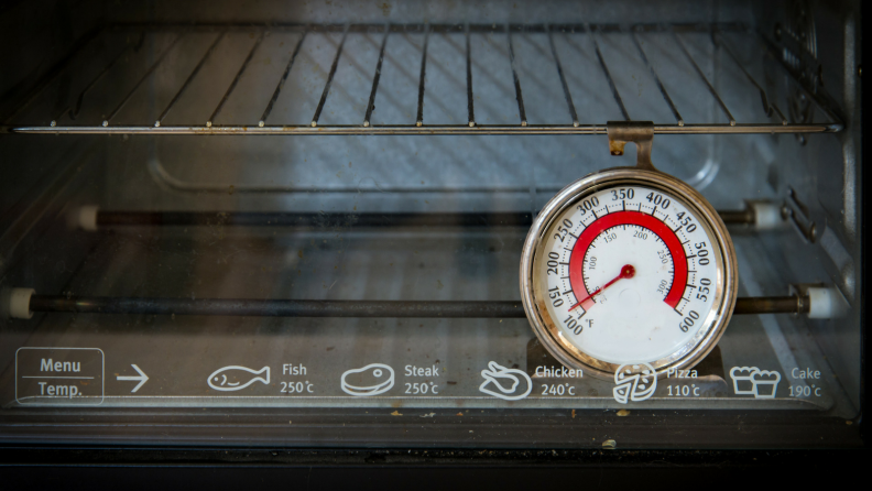 An oven thermometer hangs from an oven rack.