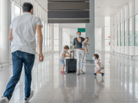 A family with three children in an airport pushing a suitcase