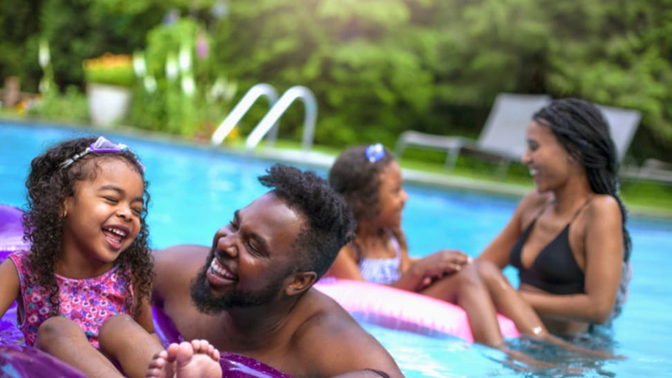 A family plays together in a swimming pool.