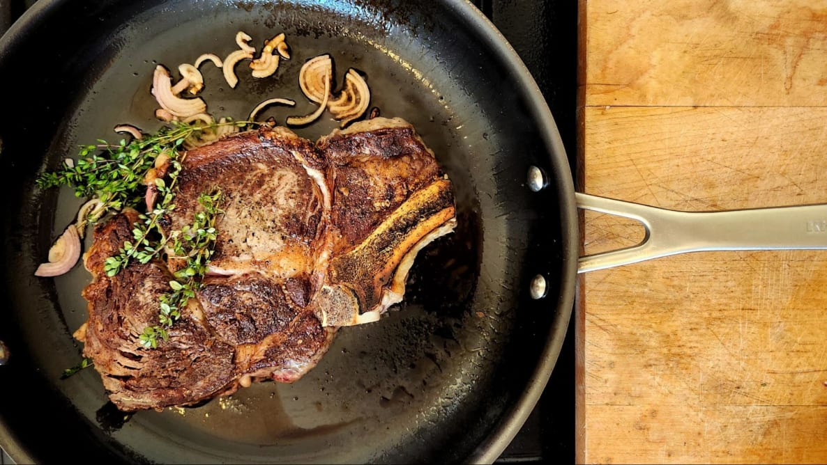 Photo of KitchenAid Nitro Carbon Steel Fry Pan cooking a seared steak and herbs.