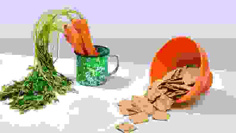 Bowls of carrots and chips sit on a surface.