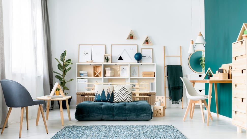 A bright home office with a modern desk on the right, a blue rug in the center, and a chair on the left