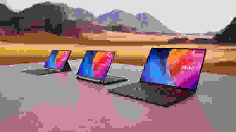 Three Asus ProArt laptops, the P16, PX13, and PZ13, sitting on a table out on a plain with mountains in the background.