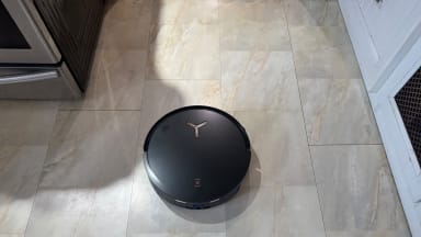 A black Deebot robot vacuum on a light tile kitchen floor
