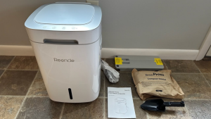 The Reencle Home Composter, which comes with an instruction manual, package of microbes, filters, and scoop.