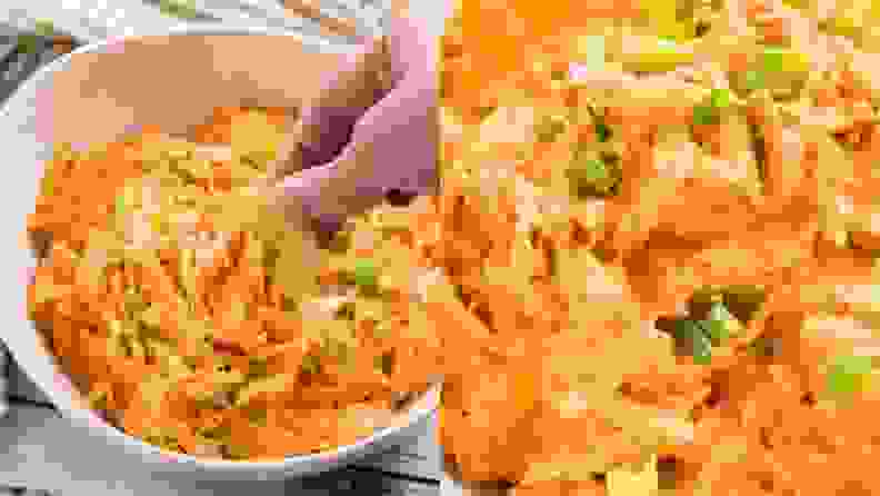 A hand digging into a bowl of buffalo chicken dip with a tortilla chip.