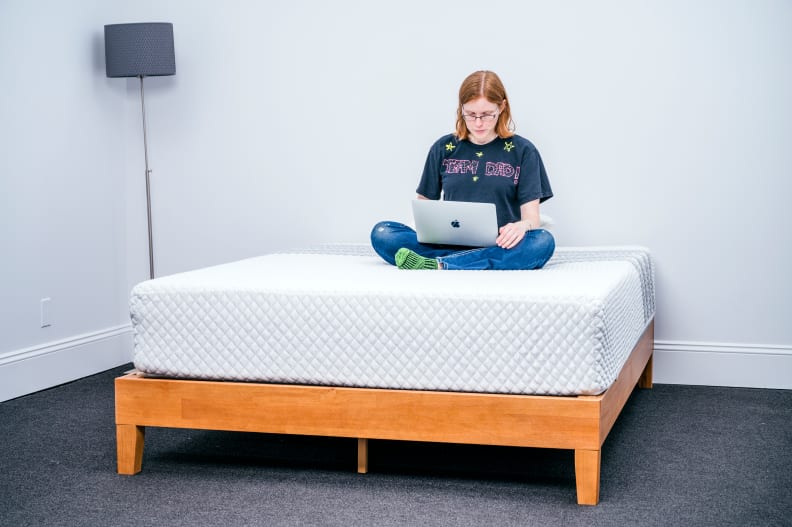 a person sits atop the Leesa hybrid working on their computer