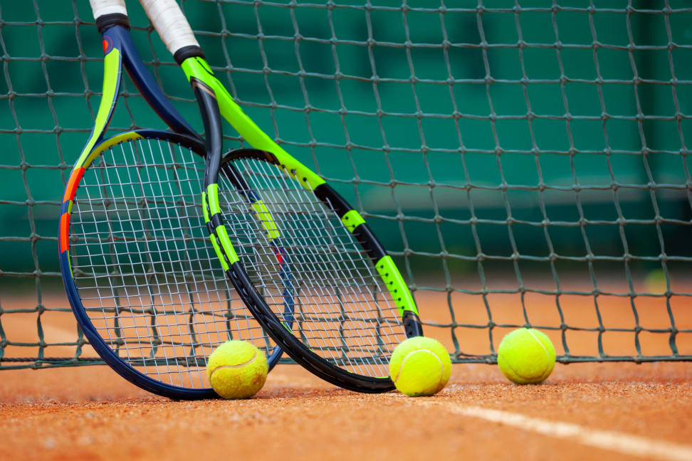 Two tennis rackets and balls leaned against the net.