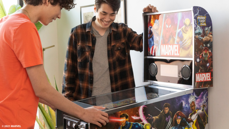 Two friends playing with the Marvel pinball machine.