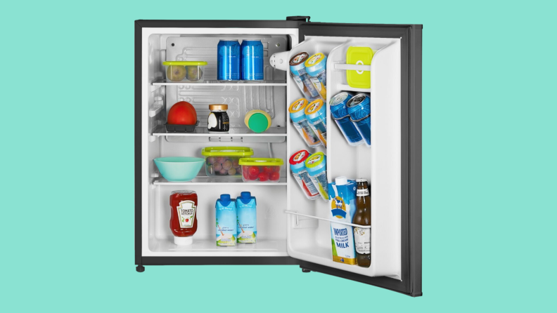 An open mini refrigerator sits on a teal background.