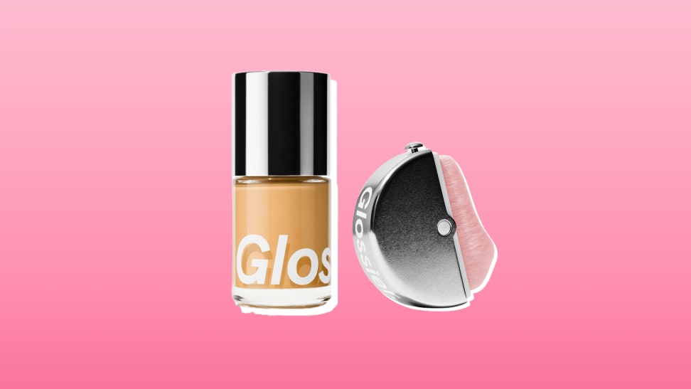 Glossier foundation and brush against a pink background.