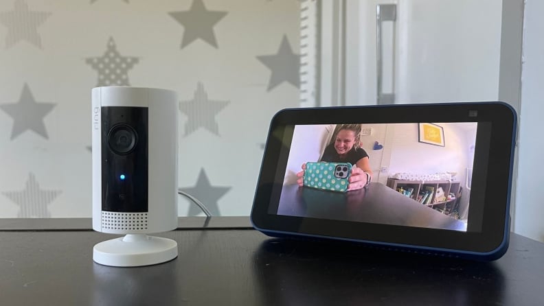 The Ring Indoor Camera sits on a brown storage desk next to a seond-gen Amazon Echo show 5