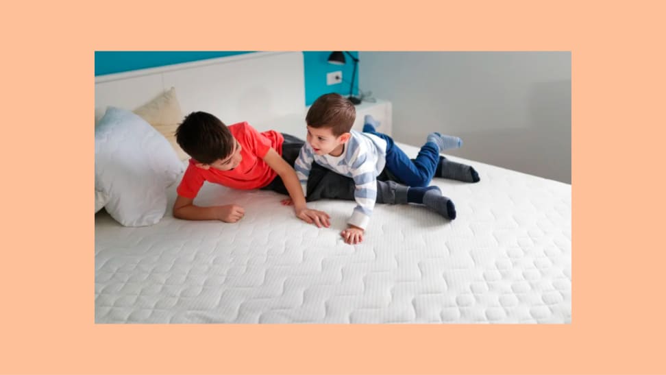 Two boys play on bare mattress