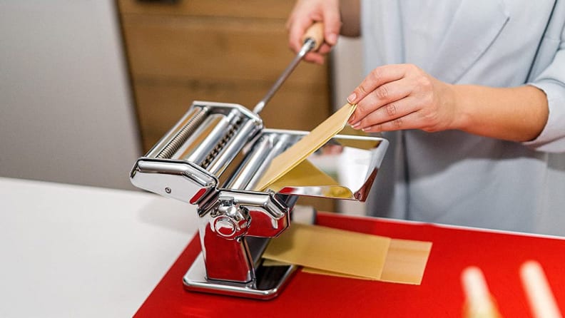 Person using pasta maker on countertop.