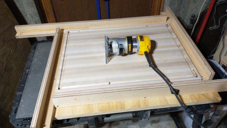 A Dewalt DWP611 Compact Router sits on a workstation.