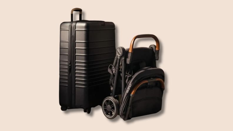 The Nuna Trvl Stroller, folded, next to a black suitcase on a tan background.