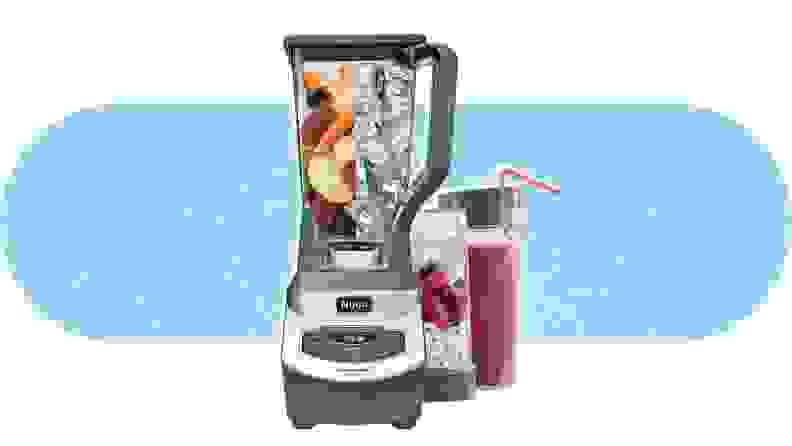 The Ninja BL660 Blender filled with ice and fruit next to two filled smoothie cups.