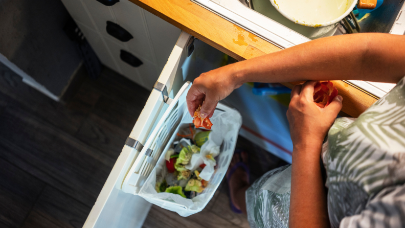 A person discards food clippings to a compost bag.