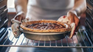 A person removes a pie from the oven.