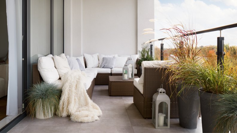 A white couch sits on a balcony surrounded by plants.