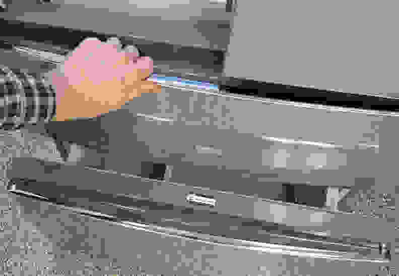A hand reaches into frame to pull open the fridge's flex drawer.