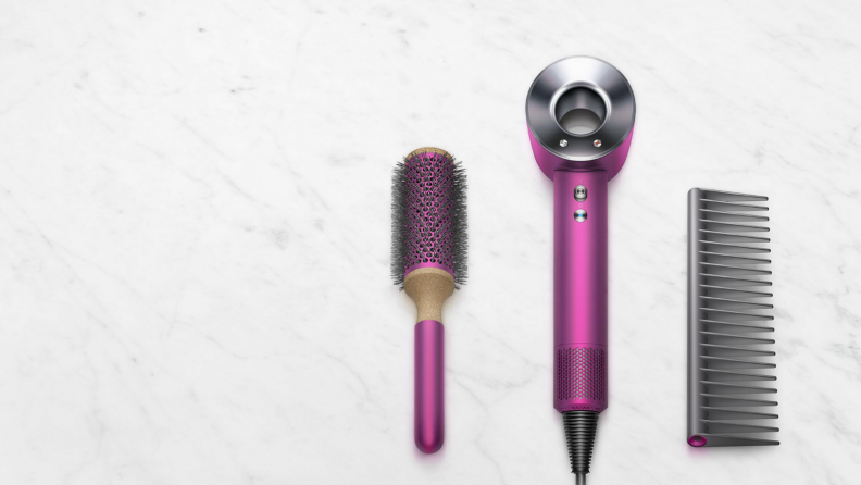 An image of a hair brush, the Dyson hair dryer, and a comb next to one another.