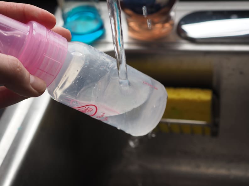 A bottle being warmed manually with hot tap water.