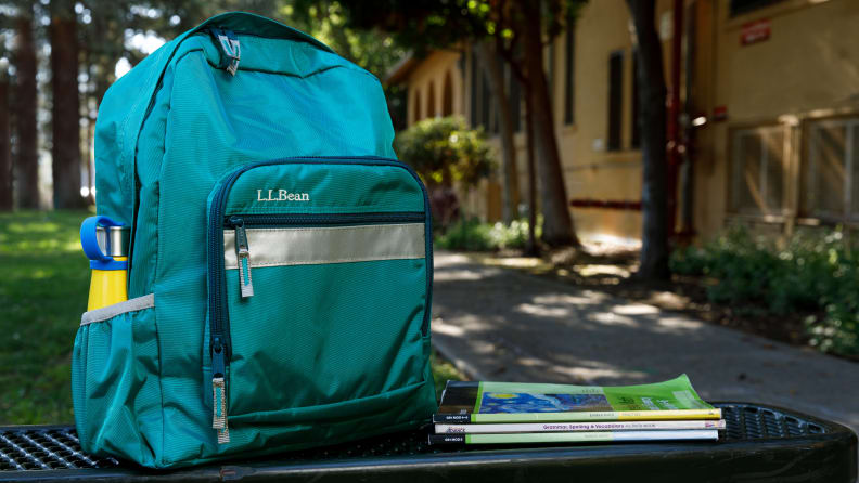 A teal green LL Bean backpack on a bench.