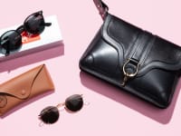 black handbag and pairs of sunglasses on pink background