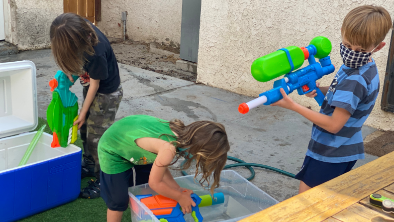 Three kids test water guns.