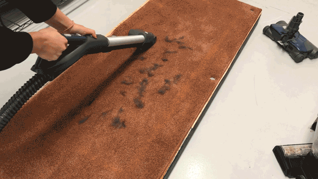 A GIF of a person using the Kenmore Pop-N-Go vacuum to clean up pet hair, on a brown carpet.