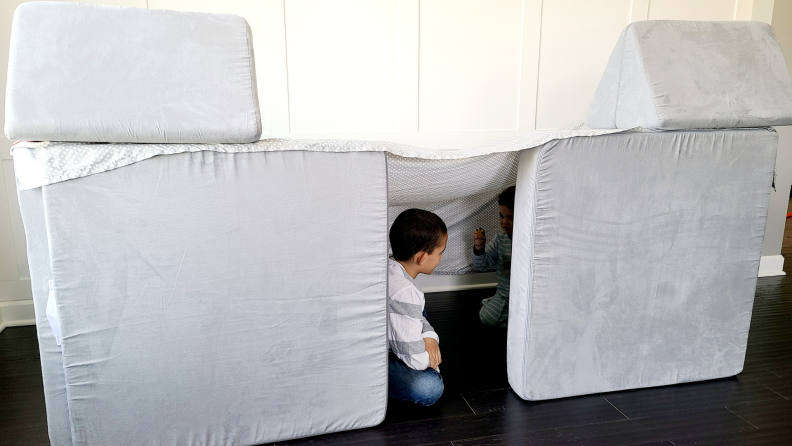 Two children play in a fort constructed from the Nugget Couch.