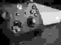 A gaming controller in front of a gaming console