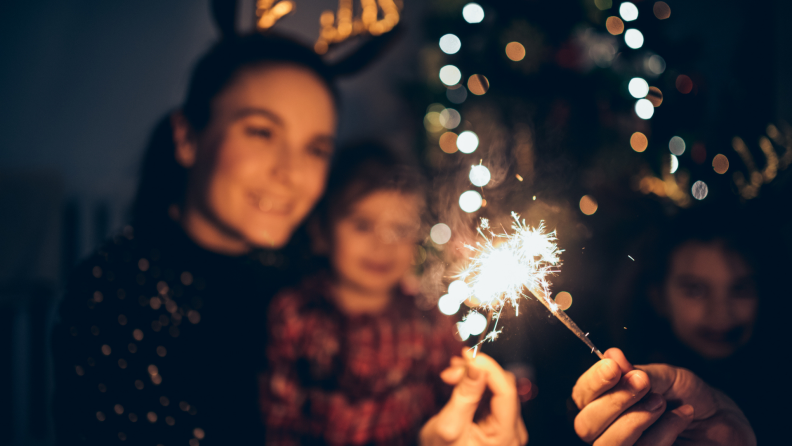 Mother and child holding up sparklers and smiling.
