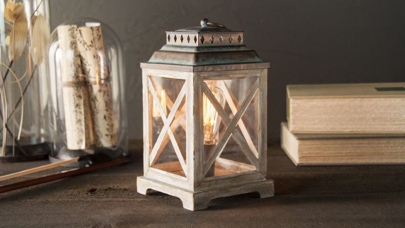 An image of a lantern-shaped wax melter on a tabletop with other neutral-toned decor items.