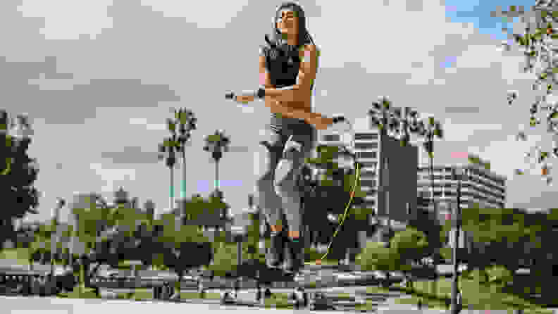 A Latina woman jumps rope at MacArthur Park in Los Angeles, California on a bright sunny day.  Horizontal image.