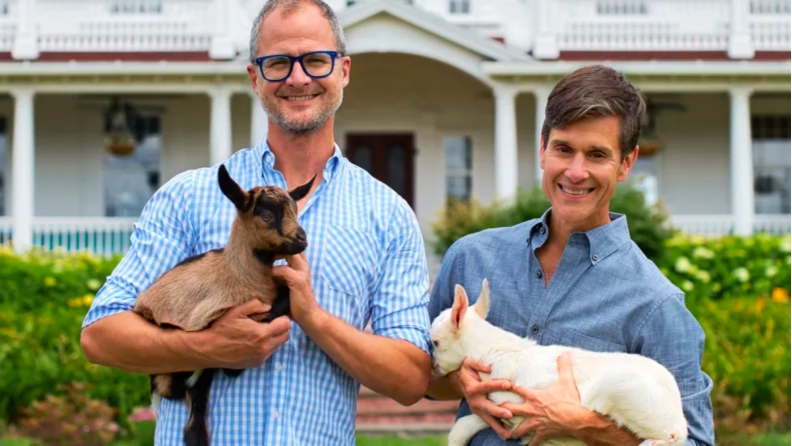 An image of Beekman 1802 co-founders Brent Ridge and Josh Kilmer-Purcell holding their dogs outside a home.