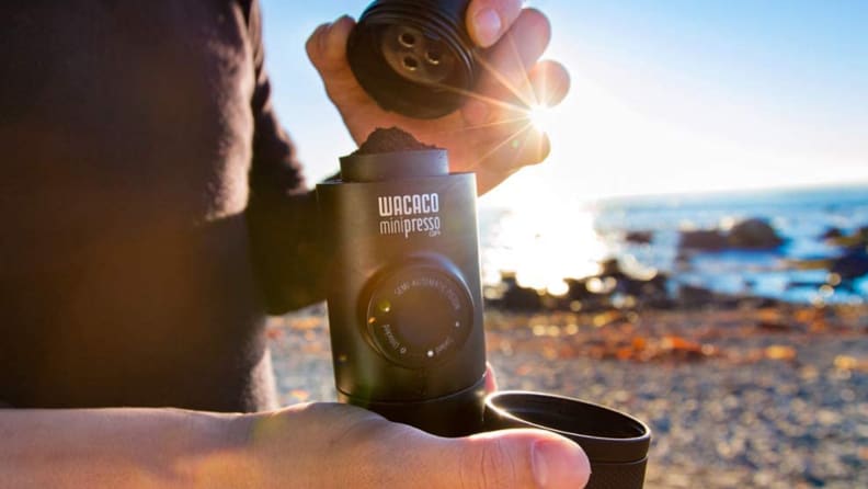 man holding portable espresso bottle by beach