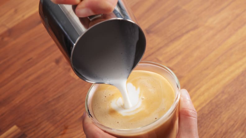 Milk being poured into a latte from the milk jug