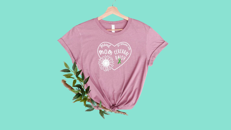 A pink Nfiniti T-shirt from Etsy on a green background