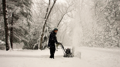 A person in winter wear puts their snow blower to good use following a heavy snowfall.