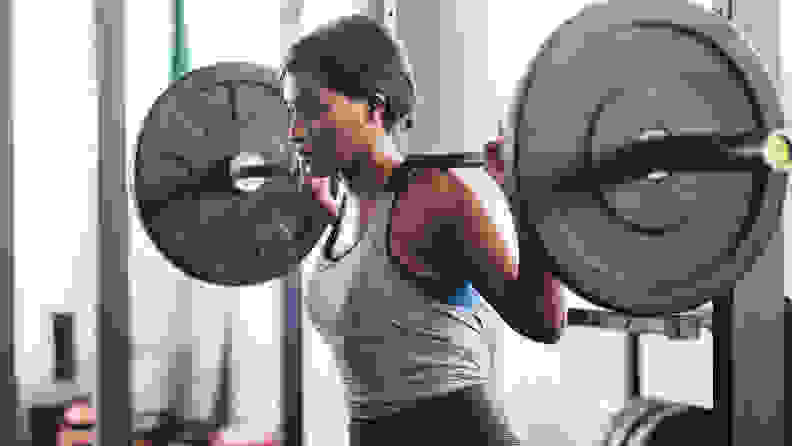 A woman holding a barbell on her shoulders.