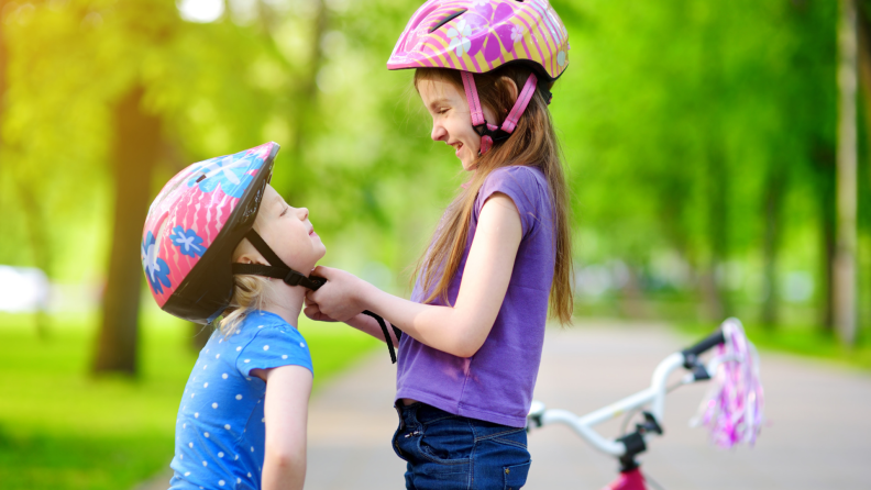 Girls putting on bike helmets